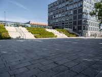 a long stairway leads up to the top of an outdoor park and plaza with landscaping along one side of the stairs