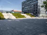 a long stairway leads up to the top of an outdoor park and plaza with landscaping along one side of the stairs