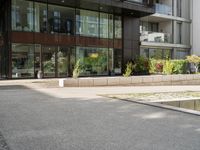 man standing in front of large, modern apartment building on paved street in urban area