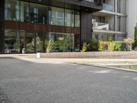 man standing in front of large, modern apartment building on paved street in urban area