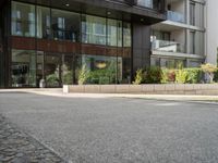 man standing in front of large, modern apartment building on paved street in urban area