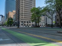 the green paint is painted on a bike path in front of an office building and large, trees