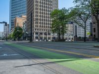 the green paint is painted on a bike path in front of an office building and large, trees