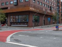 the two traffic lights are red and the intersection is blue and white and with a building with three floors