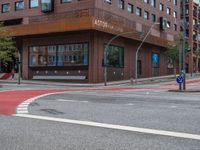 the two traffic lights are red and the intersection is blue and white and with a building with three floors