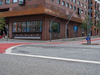 the two traffic lights are red and the intersection is blue and white and with a building with three floors