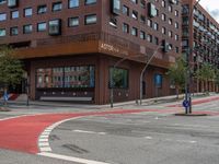 the two traffic lights are red and the intersection is blue and white and with a building with three floors