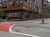 the two traffic lights are red and the intersection is blue and white and with a building with three floors