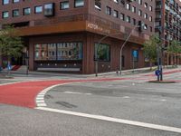 the two traffic lights are red and the intersection is blue and white and with a building with three floors