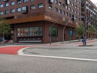 the two traffic lights are red and the intersection is blue and white and with a building with three floors