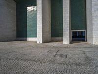 an empty area with some kind of building in the background, near concrete pillars and windows