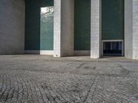 an empty area with some kind of building in the background, near concrete pillars and windows