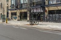 the side walk of a storefront with a bike sitting on the sidewalk and a fire hydrant