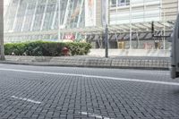 a black car driving down a road on top of bricks next to tall buildings,