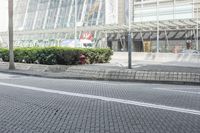 a black car driving down a road on top of bricks next to tall buildings,