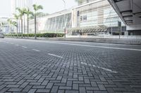 a black car driving down a road on top of bricks next to tall buildings,