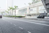 a black car driving down a road on top of bricks next to tall buildings,