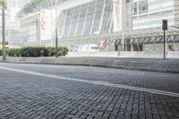 a black car driving down a road on top of bricks next to tall buildings,