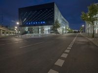 a modern architecture with glass in the center, illuminated by bright lights, stands in an empty street