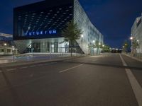 a modern architecture with glass in the center, illuminated by bright lights, stands in an empty street