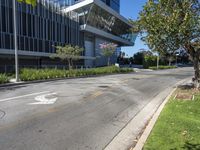 a empty road outside of a building next to a grass field and trees in the foreground