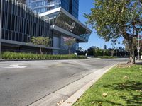 a empty road outside of a building next to a grass field and trees in the foreground