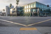 an empty street with a yellow crosswalk sign on the side of it, and two buildings in the back