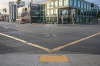 an empty street with a yellow crosswalk sign on the side of it, and two buildings in the back