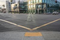 an empty street with a yellow crosswalk sign on the side of it, and two buildings in the back