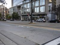 an empty street next to buildings and a bus stop sign with red and white numbers