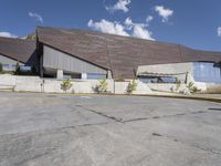 a gray building sitting on top of a parking lot next to mountains with trees near it