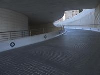 an exterior view with concrete, arched and rounded windows, and grey and white concrete flooring, and a curved building made to resemble c20