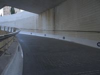 an exterior view with concrete, arched and rounded windows, and grey and white concrete flooring, and a curved building made to resemble c20