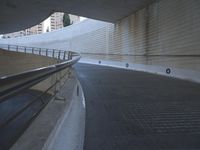 an exterior view with concrete, arched and rounded windows, and grey and white concrete flooring, and a curved building made to resemble c20