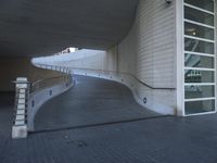 an exterior view with concrete, arched and rounded windows, and grey and white concrete flooring, and a curved building made to resemble c20