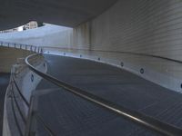 an exterior view with concrete, arched and rounded windows, and grey and white concrete flooring, and a curved building made to resemble c20