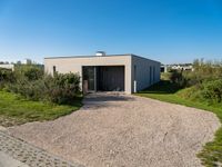 a home is constructed with concrete and grass on the grass, with a shed and garden area