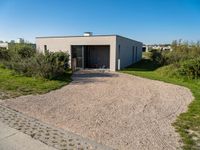 a home is constructed with concrete and grass on the grass, with a shed and garden area