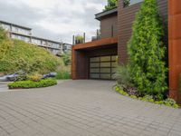 the driveway is lined with potted plants and trees, along with a paved sidewalk