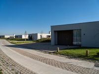 a long driveway next to a white and brown building with a gated in area