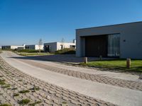 a long driveway next to a white and brown building with a gated in area