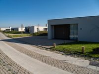 a long driveway next to a white and brown building with a gated in area