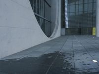 a white cement and glass walkway in front of a building with the window on it