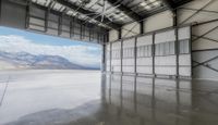 an indoor warehouse with a large open floor area and mountains in the background behind it