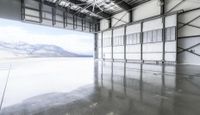 an indoor warehouse with a large open floor area and mountains in the background behind it