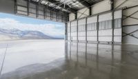 an indoor warehouse with a large open floor area and mountains in the background behind it