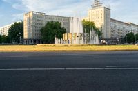 a water fountain and fountain statue in front of a tall building with trees near by