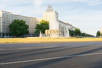 a water fountain and fountain statue in front of a tall building with trees near by