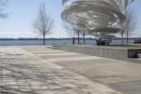 a sculpture is set beside the water's edge at a lakefront area with benches on either side