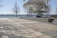 a sculpture is set beside the water's edge at a lakefront area with benches on either side